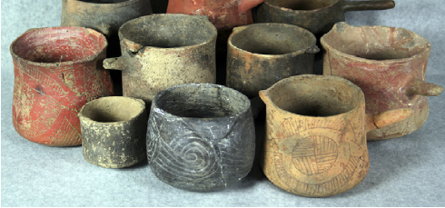 A collection of ancient Mississippian-style pottery vessels and ceramic cups used historically for brewing and serving Yaupon tea.