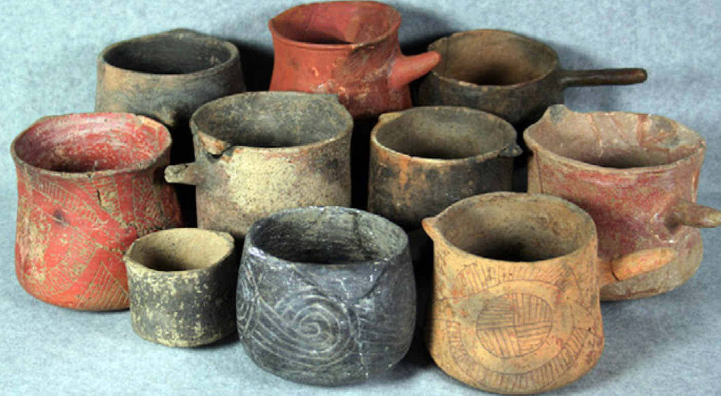 A collection of ancient Mississippian-style pottery vessels and ceramic cups used historically for brewing and serving Yaupon tea.