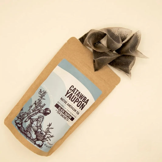 Catawba Yaupon Black loose leaf tea spilling out of a kraft paper pouch with a light blue label.