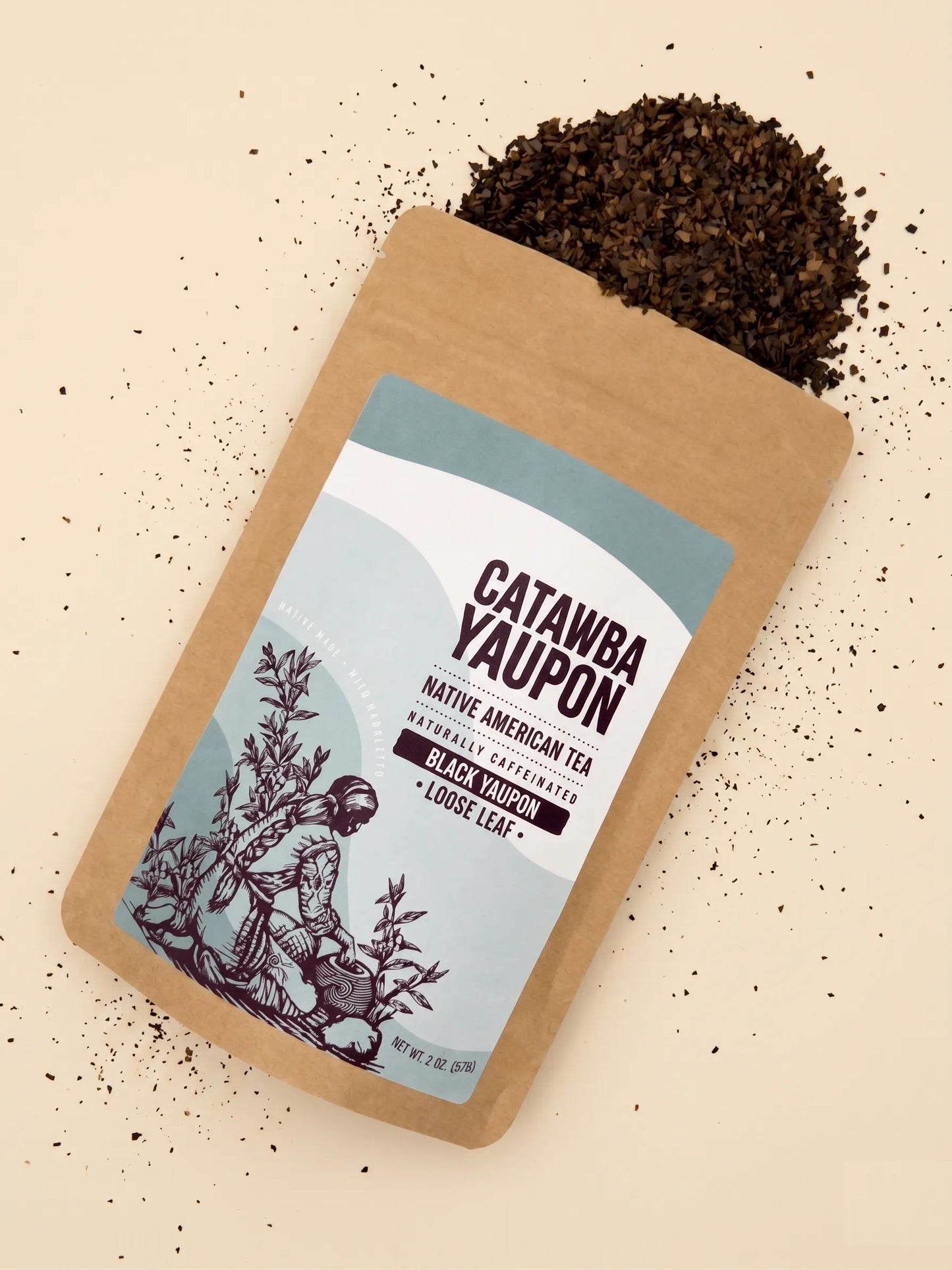 Catawba Yaupon Black loose leaf tea spilling out of a kraft paper pouch with a light blue label.