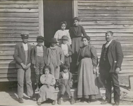 A historical black-and-white photograph depicting a Catawba family standing together in front of a wooden-sided home.