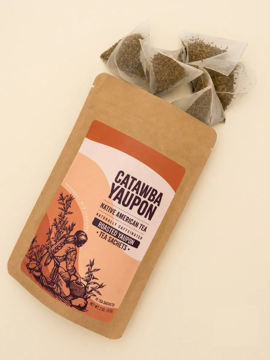 A 2 oz pouch of naturally caffeinated Roasted Yaupon tea displayed with several mesh pyramid tea bags.